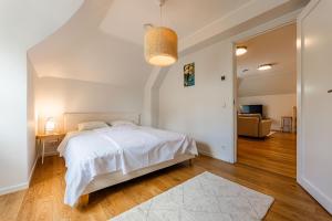 a white bedroom with a bed and a living room at Komandandi City Center Apartments in Kuressaare