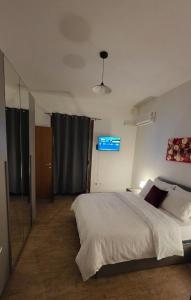 a bedroom with a large white bed and a television at Mari del sud in Bagheria +1 photo