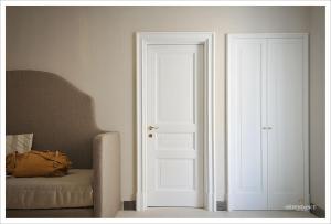 a white door leading to a room with a white bed at La Dépendance Hotel in Noto