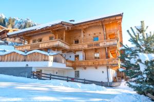 un gran edificio de madera con nieve en el suelo en Aparthaus Sonnenhof, en Alpbach