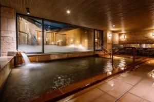 a pool of water in a building with a waterfall at Aki Grand Hotel & Spa in Miyajima +42 photos