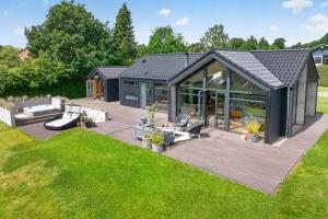 a black cottage with a deck and a lawn at Luxurious Holiday Home with Sauna & Outdoor Hot Tub in Hejls