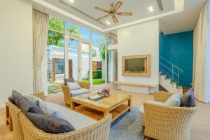a living room with a couch and chairs and a tv at Andaman Pool Villas, Maikhao Beach Phuket in Mai Khao Beach