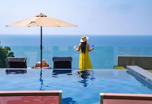 a woman in a yellow dress standing next to a swimming pool at Ayara Kamala Resort & Spa in Kamala Beach