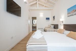 a white bedroom with a bed and a tv at Karú Suites in Cagliari