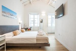 a bedroom with a large bed and a flat screen tv at Karú Suites in Cagliari