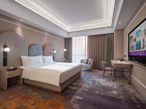 a hotel room with a large bed and a desk at Mercure Beijing Downtown in Beijing