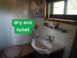 a bathroom with a white toilet and a sink at Ecologic glamping in Estevais