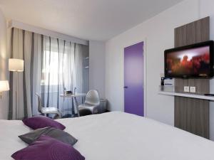 a hotel room with a bed and a flat screen tv at ibis Styles Grenoble Centre Gare in Grenoble