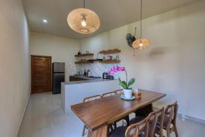 a kitchen and dining room with a wooden table and chairs at Rest U Guest House in Nusa Penida