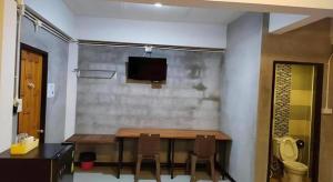 a dining room with a table and a tv on a wall at Kidthuengpark in Ban Nong Faep