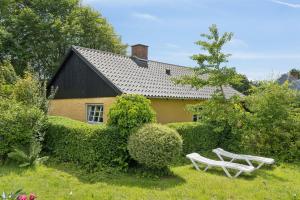 a house with two white benches in the yard at Idyllic Old Cottage With Low Ceilings in Bredebro