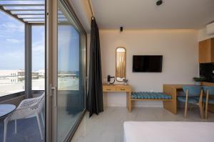a room with a bedroom with a desk and a balcony at Falasarna Bay Hotel in Falasarna