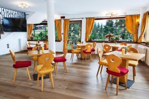 un restaurante con mesas y sillas de madera y ventanas en Hotel Erika, en Madonna di Campiglio