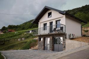 a white house with a balcony on a hill at Leona in Kamešnica