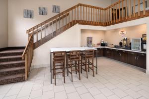 a kitchen with a bar with stools and a staircase at Super 8 by Wyndham Longmont/Twin Peaks in Longmont