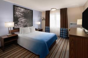 a hotel room with a bed and a television at Super 8 by Wyndham Longmont/Twin Peaks in Longmont