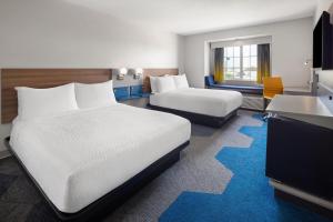 a hotel room with two beds and a desk at Microtel Inn & Suites - Kearney in Kearney +23 photos