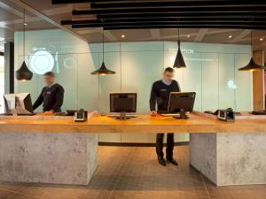 two men standing at a counter with their computers at ibis Genève Centre Nations in Geneva