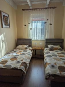 two beds sitting in a room with a window at Pszczeli Ogród - dom na wyłączność z jacuzzi ze świeżą wodą in Dęba Koliszowy