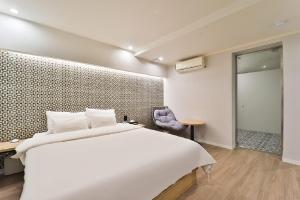 a bedroom with a large white bed and a chair at Jamsil Tomgi Hotel in Seoul