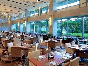 a dining room with tables and chairs and windows at Pullman Xiamen Powerlong in Xiamen