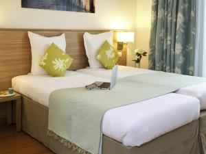 two beds in a hotel room with a laptop on top at Aparthotel Adagio Paris Vincennes in Vincennes