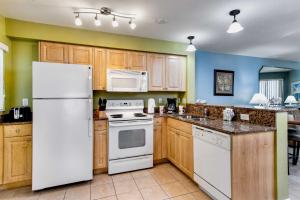 a kitchen with white appliances and wooden cabinets at Surf Beach Resort by Sunsational Beach Rentals in St. Pete Beach