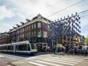 a bus driving down a street in front of a building at ibis Styles Amsterdam City in Amsterdam