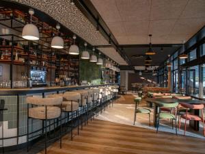 a restaurant with a bar with chairs and tables at Mercure Toulouse Aéroport Golf de Seilh in Seilh