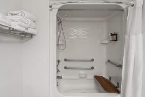 a white bathroom with a shower with towels at Travelodge by Wyndham Gardiner Yellowstone Park North Entr in Gardiner +55 photos