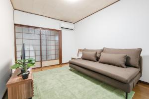 a living room with a couch and a tv at Imafuku Happiness Villa in Osaka