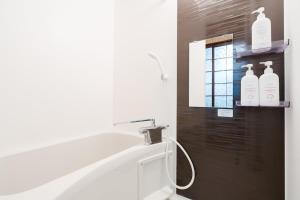 a bathroom with a shower with three bottles on the wall at Imafuku Happiness Villa in Osaka