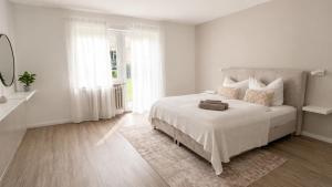 a white bedroom with a large bed with white sheets at Ferienwohnung an der Steinmauer in Bad Kissingen