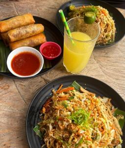 a table with two plates of food and a glass of orange juice at Firefly Treehouse Cafe and Bar in Ytaya