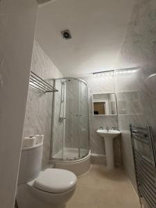a bathroom with a shower and a toilet and a sink at Milverton Court by OYO in Manchester +24 photos