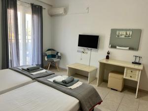 a bedroom with two beds and a desk and a television at Heaven Studios & Apartments in Stalís