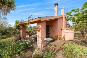 a small pink house with a table outside at Villa Anna con giardino in Flussio