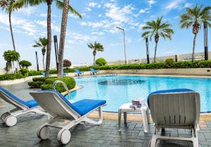 a pool with two chairs and a table and palm trees at The Palazzo Hotel in Bangkok