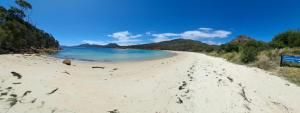 a sandy beach with blue water and mountains in the background at Bicheno Bell in Bicheno