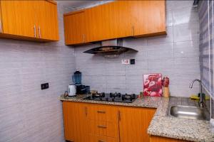 a kitchen with wooden cabinets and a stove top oven at Seven Hills Suites in Makurdu