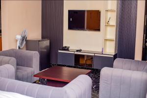a living room with chairs and a tv and a table at Seven Hills Suites in Makurdu