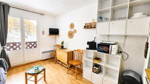 a kitchen with white cabinets and a desk in a room at Cozy studio in La Foux
