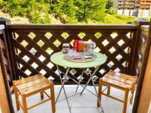 a green table with glasses and two chairs on a balcony at Cozy studio in La Foux