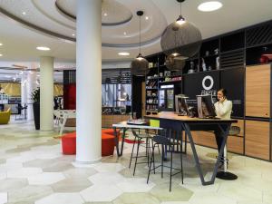 a woman sitting at a table in a lobby at Aparthotel Adagio Köln City in Cologne