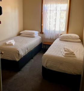 two beds in a bedroom with towels on them at Branxholm Hotel in Branxholm