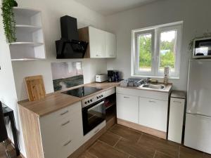 a kitchen with white cabinets and a sink and a refrigerator at Ferienhaus Calle in Bücken +20 photos