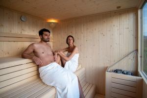 a man and woman sitting in a sauna at Albergo Bucaneve in Malosco
