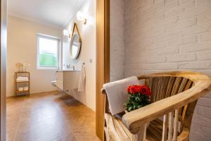 a room with a chair with a vase of red flowers at Dworek Biebrzański in Augustów +70 photos