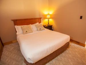 a bedroom with a large white bed with a lamp at Timberland Inn in Kenora